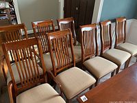 All eight chairs arranged around a dining table showing front view of slatted backs and upholstered seats