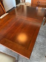 Close-up of tabletop showing inlaid wood accents forming a decorative border, medium brown wood finish.