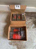 Boxes open showing multiple plastic cases of Accuset angled finish nails and staples inside on a concrete floor.