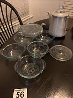 Photo showing aluminum percolator with glass knob lid and multiple blue glass bowls and trivet on a table.