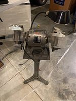Front view of Duracraft grinder and buffer mounted on metal stand with attachable flexible lighting and wheel safety shields.