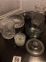 Photo showing assorted glass items including bowls, candy dish, canister and some coasters on a dark surface.