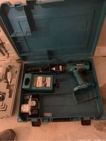 Makita cordless drill and charger in open carrying case, showing all items and case interior.