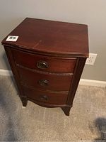 Front view of a 3-drawer vintage wooden night stand showing dark brown finish and brass drawer pulls.