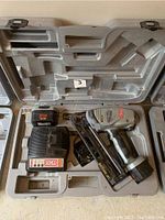 Overview of the kit components inside a molded plastic carrying case: finish nailer, battery, and charger.