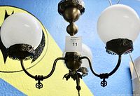 Front view of the antique brass three globe chandelier showing white globes and decorative metal details
