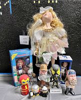 Photo of porcelain ballerina doll, various character bobbleheads and figures including Headliners football player, Yellowjacket, Duck Dynasty, Thor, and Black Cat Vinylmation.