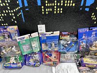 Photo showing multiple Starting Lineup action figures in original cards, mostly baseball players with one football action figure, plus some other sports collectible boxes.
