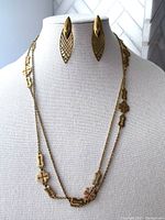 Front view of gold tone lattice drop earrings displayed on mannequin with matching decorative chain necklace.