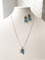 Photo of a mannequin bust displaying silver tone necklace with turquoise mosaic eagle pendant and matching turquoise beaded chandelier earrings.