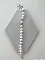 Full length image of the white freshwater pearl bracelet laid flat showing the size and individual pearls with silver beads