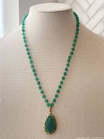 Full view of the necklace displayed on a bust showing the green onyx beads and the pendant.