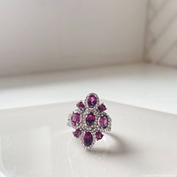 Front view of cocktail ring showing pink faceted gemstones and surrounding white topaz stones set in sterling silver.