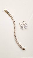 Full view of the goldplated sterling silver tennis bracelet and cubic zirconia drop earrings on a white background.