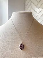 Front view of the necklace with chain and oval cluster pendant visible on fabric display stand.