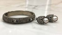 Silver tone Art Deco style bangle bracelet with geometric patterns and inset clear rhinestones, clasp visible