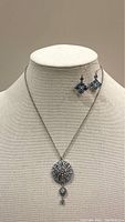 Full view of the sky blue rhinestone necklace pendant necklace and matching earrings on display bust.