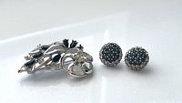 Photo of vintage dome rhinestone clip-on earrings and silver-tone floral brooch, showing top view of each item