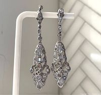 Front view of both vintage silver tone chandelier earrings hanging, showing clear rhinestones and detailed metalwork