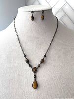 Full front view of tiger's eye necklace on display with matching earrings on a bust form