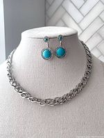 Photo of silver tone wide chain necklace on display bust with matching faux turquoise drop earrings.