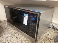 Front view of Panasonic microwave showing the digital control panel and LED display with brand sticker and lot number label.