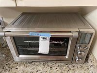 Front view of stainless steel Breville toaster oven showing exterior, glass door and handwritten dimensions label
