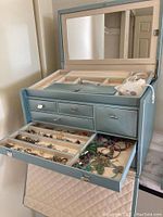 Open jewelry box showing top tier compartments with various bracelets and necklaces