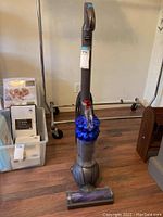 Full side view of the Dyson DC50 upright vacuum cleaner showing handle, dust bin with blue cyclone cones, ball base, and brush head.