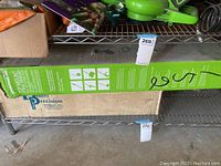 Metal shelf with Greenworks string trimmer box and Dillon Precision box