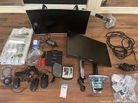 Overall view of HP curved and Samsung flat monitors with mounts, computer mice, cables, power adapter, and other accessories on wooden floor.