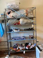 Full view of metal wire storage rack with four shelves filled with large bags and various items