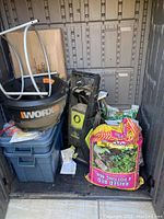 Interior overview showing Sun Joe pressure washer, WORX bucket, grey bins and soil bags
