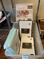 Overall view of the packaging and arrangement of mattress protector, sheets, and bed underpad in storage bin