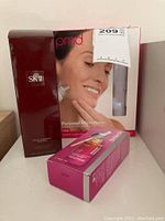Photo showing PMD Personal Microderm Pro box with face image, SK-II Facial Treatment Essence bottle box, and separate boxed facial lotion.