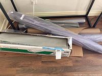 Three rolls of plastic sheeting and their boxes arranged on floor.