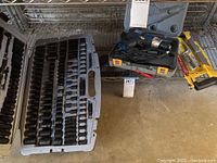 Wide view of wrench set, electric screwdriver in carrying case, and hand saw on floor.