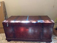 Front view of the trunk showing the crocodile pattern material, wood edges, and lock hardware