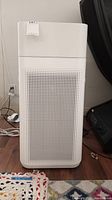 Front view of white Winix PlasmaWave 2.0 air purifier showing perforated panel and plugged in power cord.