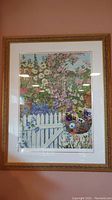 Full view of the framed floral print showing flowers, white picket fence, and garden setting.