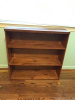 Front view of wood bookshelf showing three shelves and overall shape.
