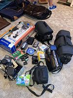 Full view of the lot showing all cameras, tripods, cases, film rolls, and accessories as laid on the floor.