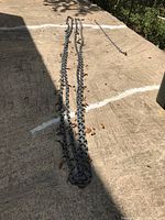 Two metal chains laid out on concrete, one very long chain around 40 feet and one shorter chain about 3 feet long, showing length and link details.