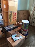 Multiple boxes stacked with a large Golden Sleigh Christmas tree box, various decorative tins with Christmas themes, and boxes with smaller items like ornaments and figurines.