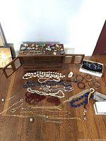 Photo of costume jewelry laid out on floor and jewelry boxes on top of small wooden furniture