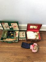 Green carrying case with miniature Singer sewing machine, sewing patterns/manuals, and sewing notions box visible inside.
