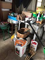 Photo showing baskets, garden tools, fertilizer bottles, birdhouse, and buckets with garden supplies.