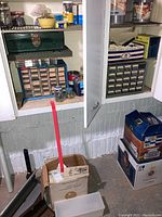 Photo of a metal toolbox and a plastic hardware storage cabinet with small drawers filled with various hardware items, jars, and other containers nearby.