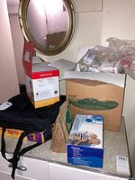 Photo showing the mirror, water pitcher box, and several items packed in boxes and bags on a surface.