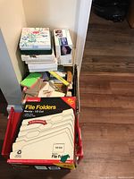 Stack of file folders, notepads, and assorted boxes arranged in corner, showing size and types of items